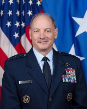 A portrait of U.S. Air Force Lt. Gen. Michael Downs in his dress uniform in front of a U.S. flag.