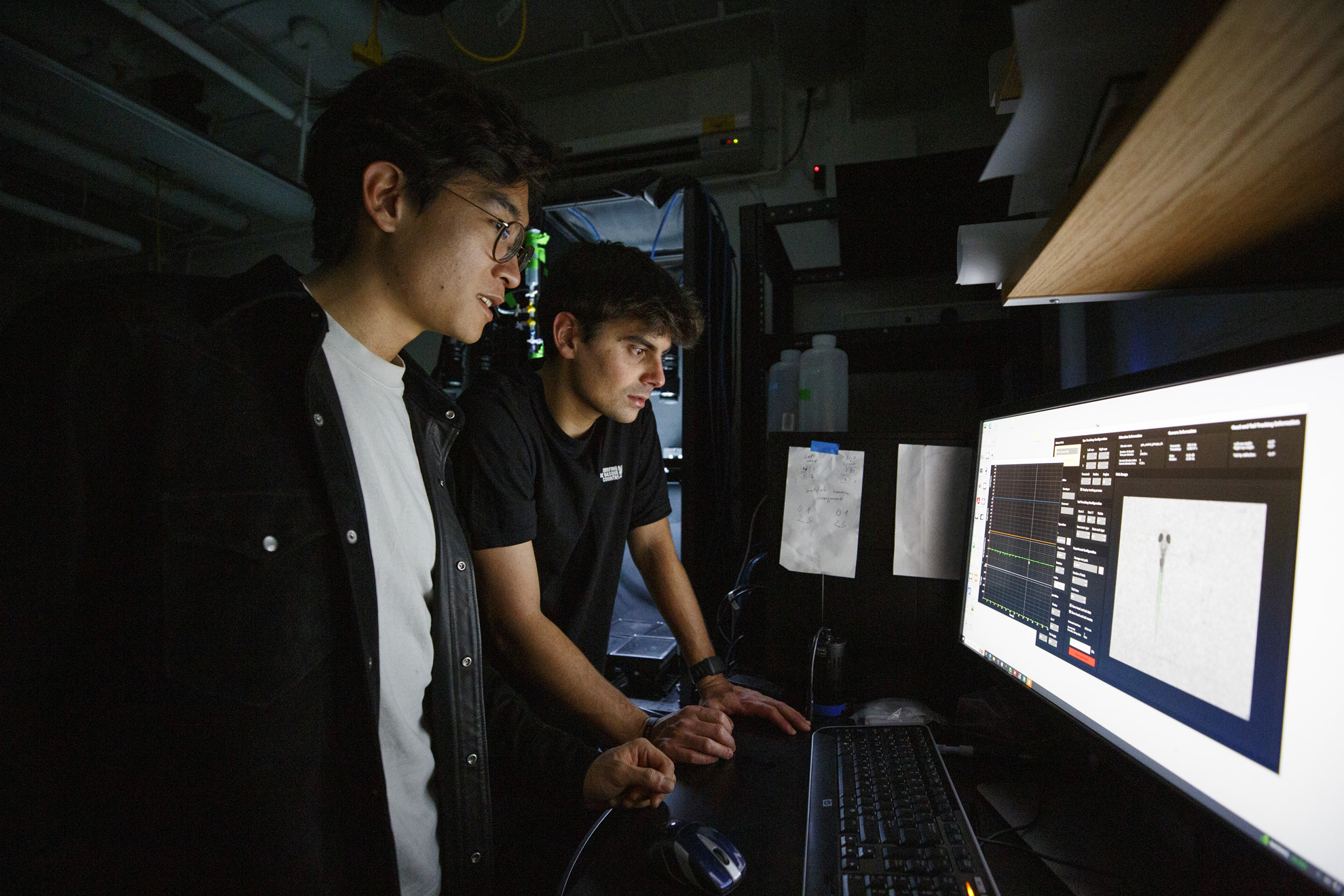 Alex Chen (left) and Marc Duque Ramirez examine the movements of days-old zebrafish captured through a sophisticated optical arrangement as part of ongoing investigation.