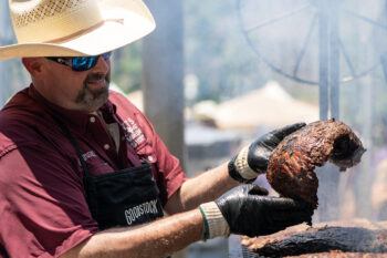 An image depicting a man examining meat after removing it from a grill.