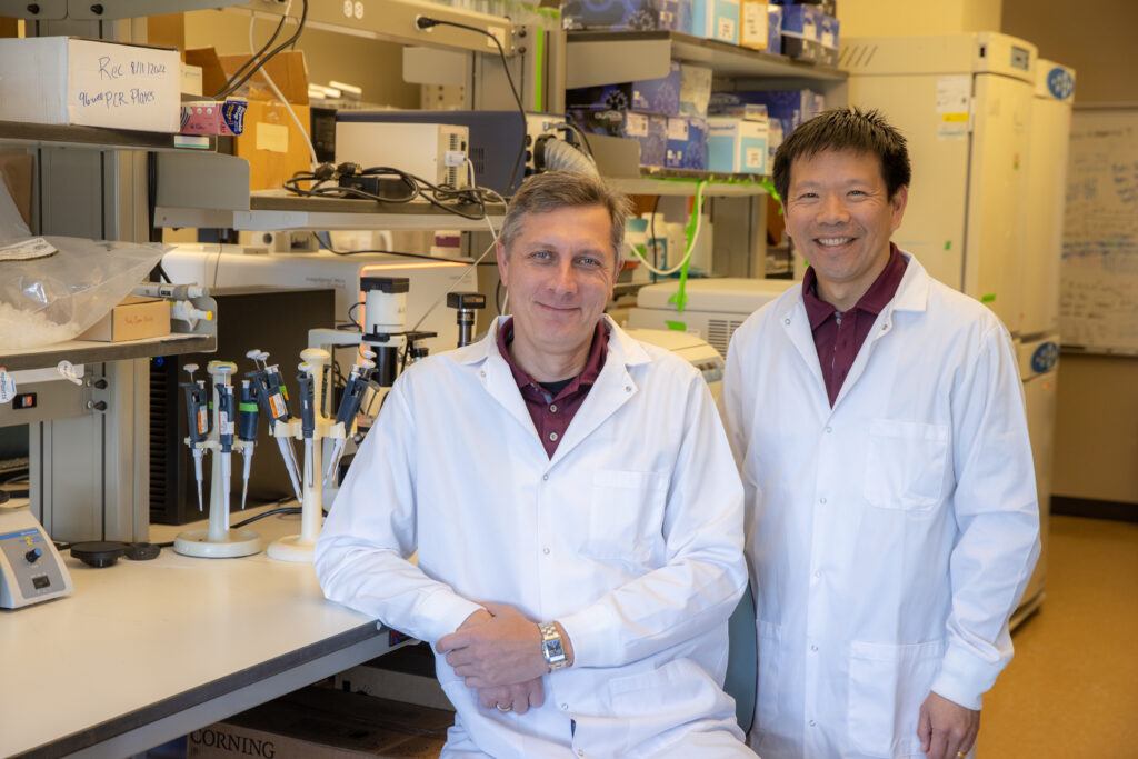 An image depicting two researchers posing in a laboratory wearing white lab coats.