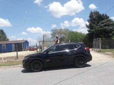 a person standing in a car so that their torso is out of the sunroof