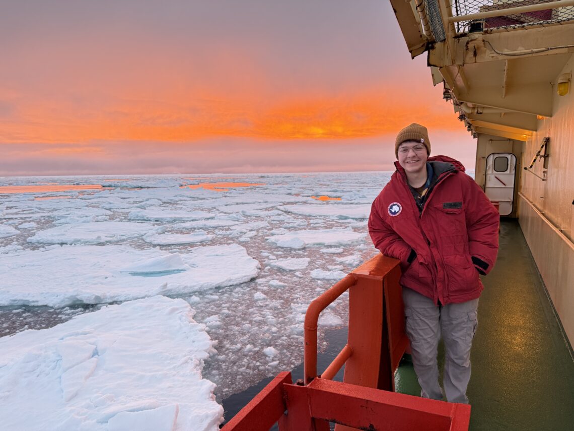 individual on a ship deck with ice in water and a crimson sky