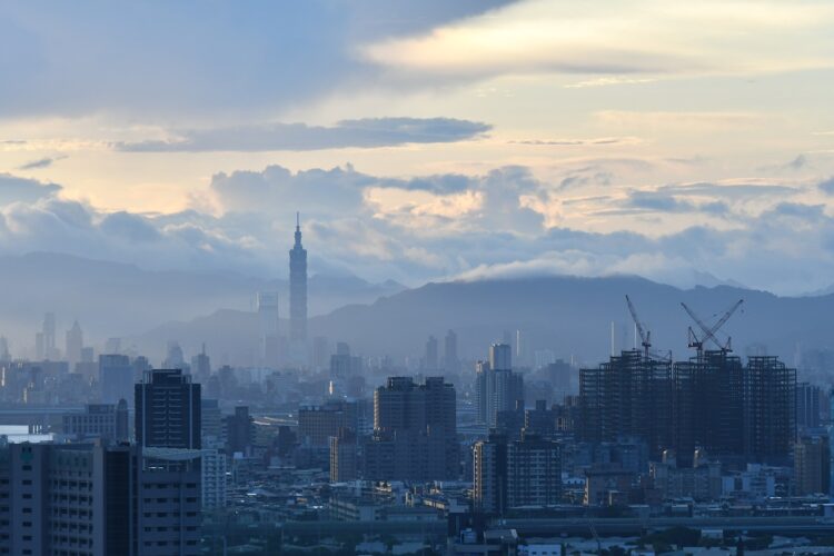 Mountains and clouds rise behind the skyline of Taipei.