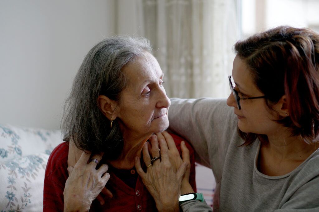 a caregiver puts her arm around a patient at home