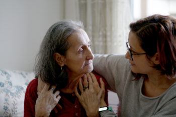 a caregiver puts her arm around a patient at home