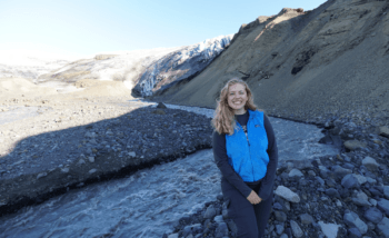 Lauren Berger poses beside a glacier in Iceland during the 2021 SAND-E Mission (Semi-Autonomous Navigation for Detrital Environments), which investigated Mars-like landscapes to analyze how sediments vary upriver and downriver and to assess rover scientific operations and navigation in these conditions.