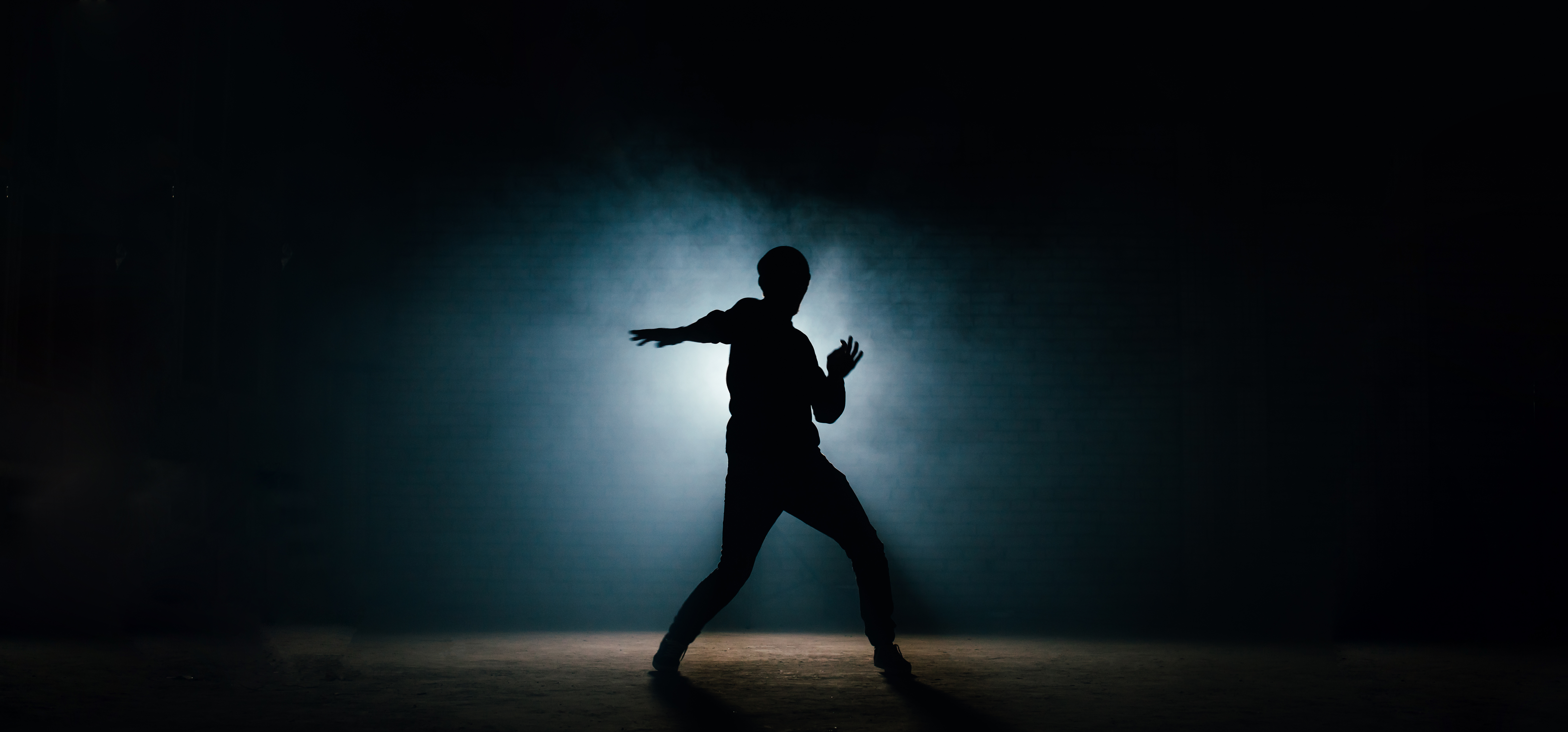 A performer stands out against a shadowy backdrop.