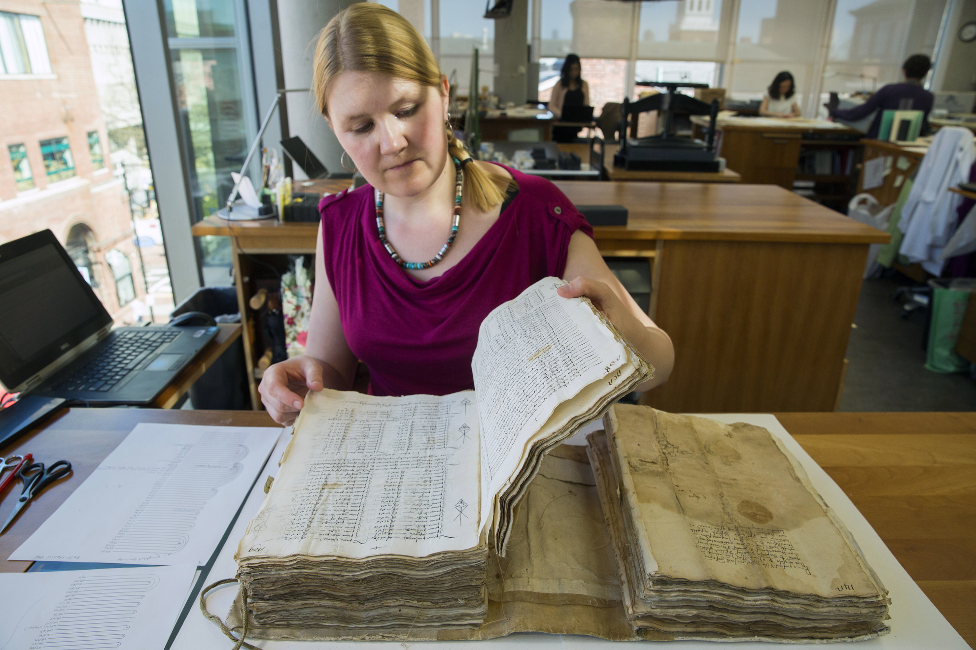 Book Conservator Katherine Beaty tends to a bound volume of business documents, including partnership agreements and related records from the Harvard Business School Baker Library.