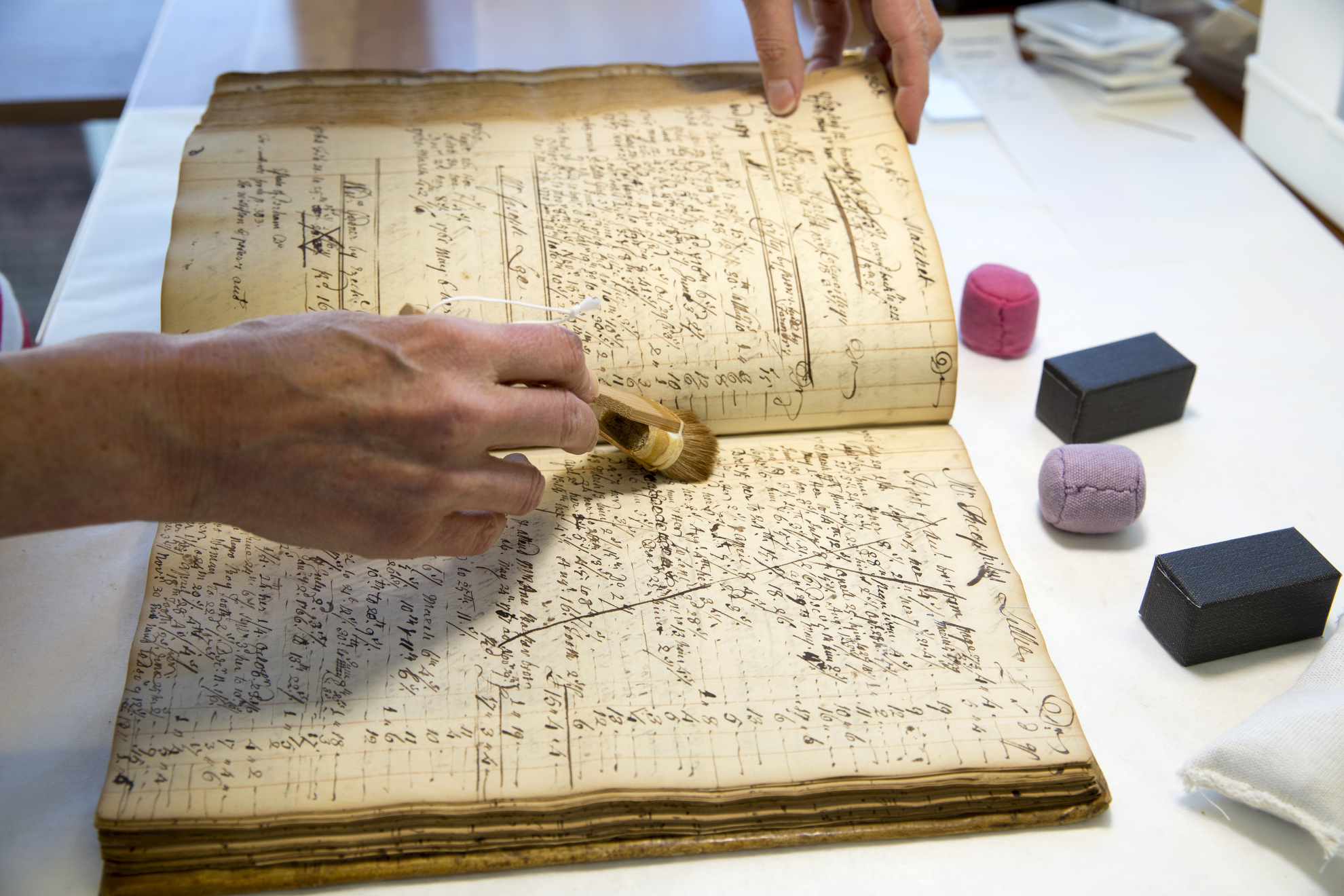 Anne Corrsin, Conservation Technician for Special Collections, cleans an account book for medical services provided by John Perkins (1698-1781) from 1744 to 1780. B MS b64. Boston Medical Library, Francis A. Countway Library of Medicine, Boston, Mass.