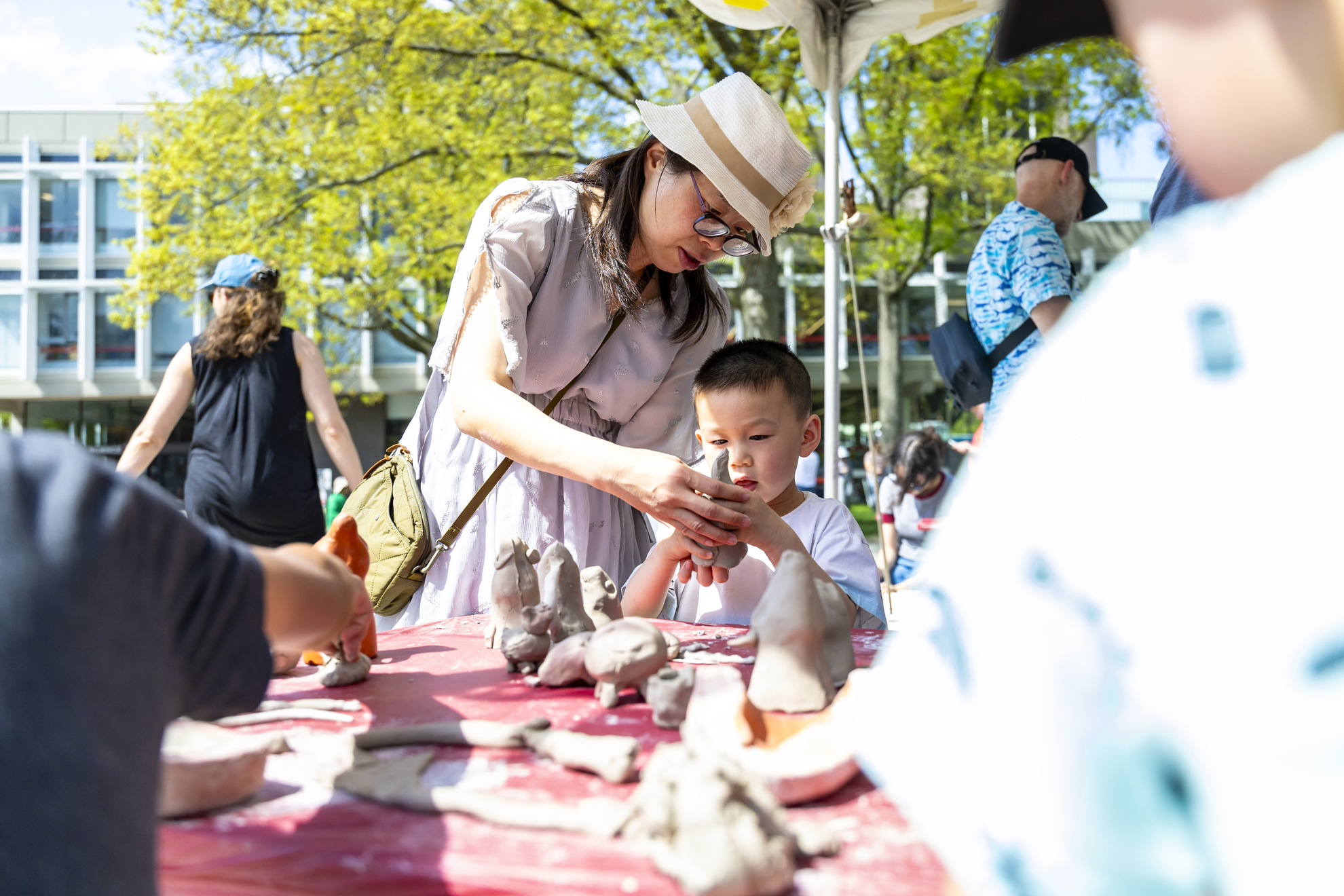 Zack Li and his mother Linghui Li shape clay together in the Science Center Plaza.