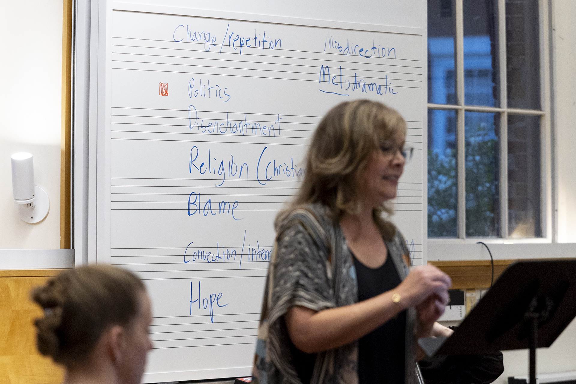 Vocalist Krista River stands before a white board featuring words like "change," "politics," "disillusionment," and religion."