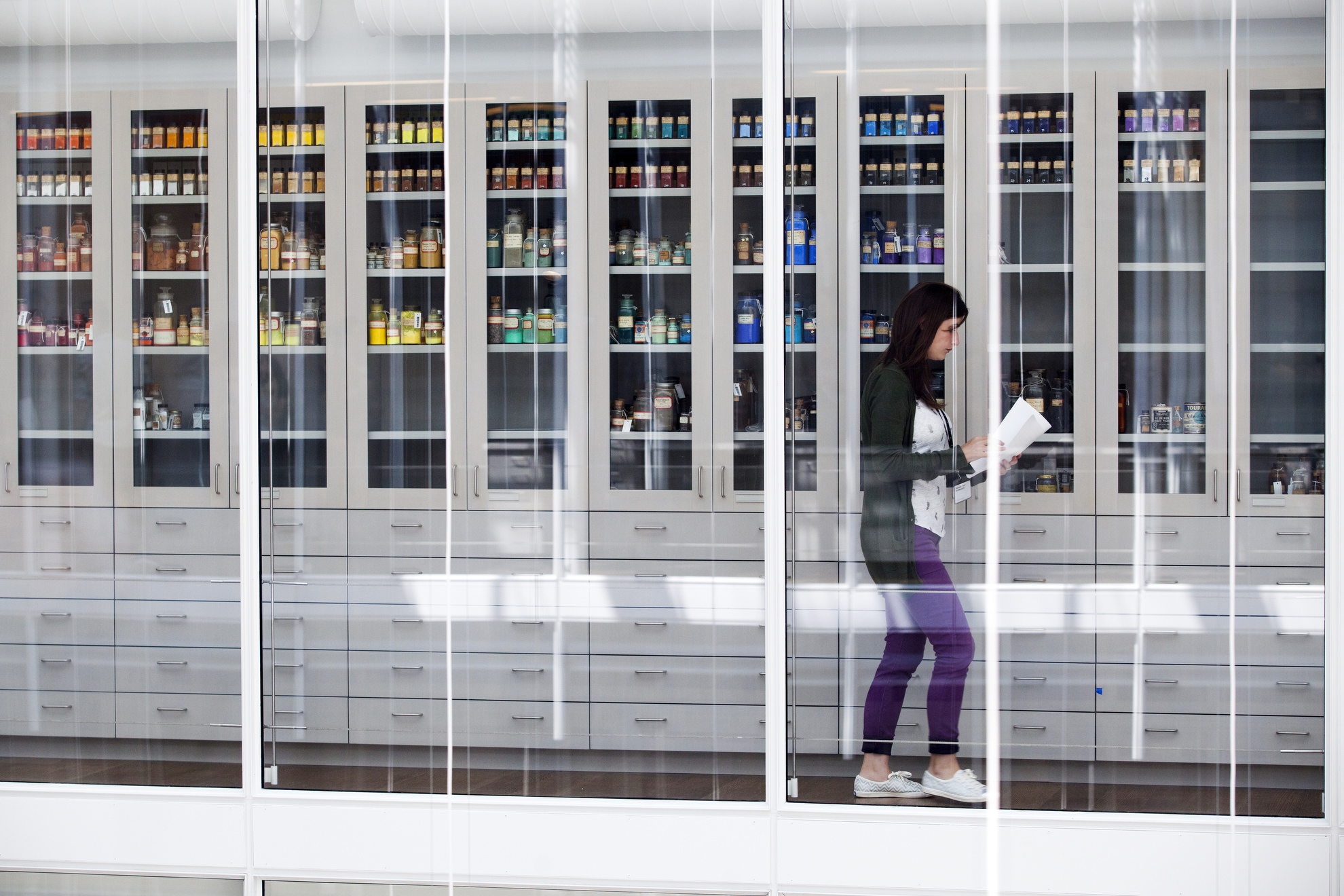 A woman strolls by the pigment collection at Harvard Art Museums.