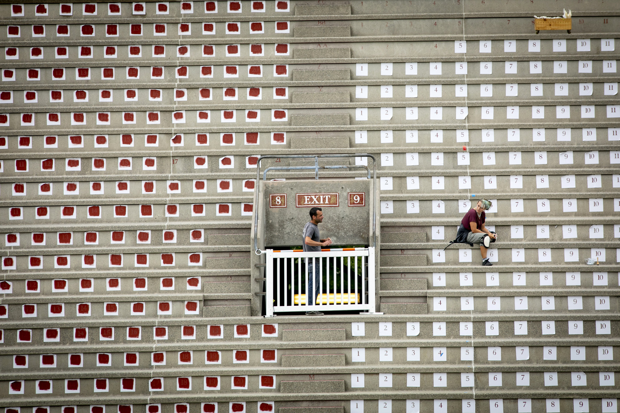 Melissa Dole reletters the seat numbers in Harvard Stadium using stencils.