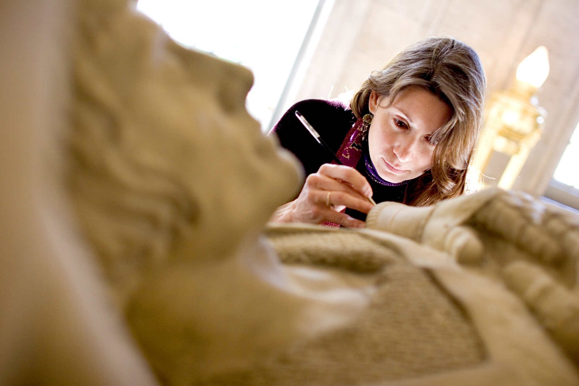 Nancy Lloyd, Objects Conservator for the Straus Center for Conservation at Harvard University, restores a fallen soldier statue in the Memorial Room at Memorial Church.
