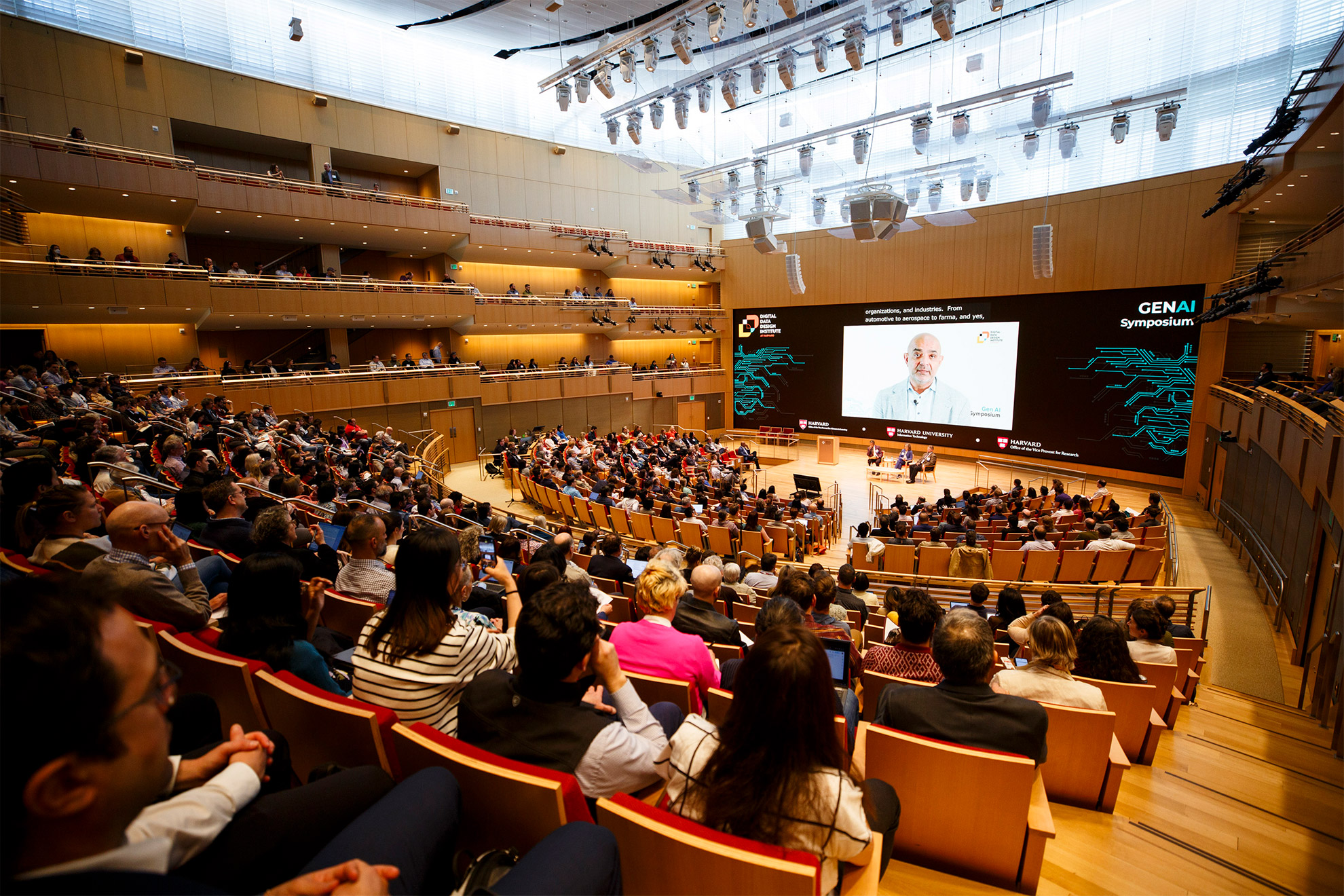 An AI representation of Karim R. Lakhani delivering opening video address.