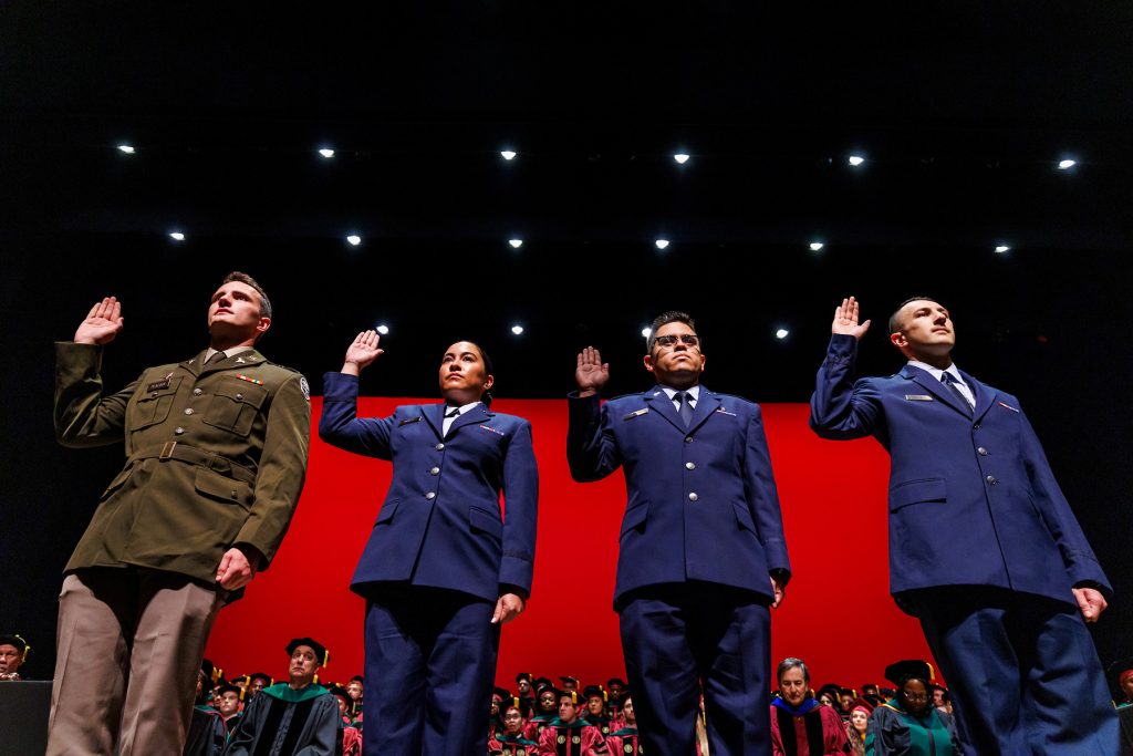 Military members of the M.D. Class of 2025, from left to right, Ryan Peacock, Erika Balazs, Mike Llerena, and Nathan Steineck, renew their oath of service during Saturday’s commencement ceremony.