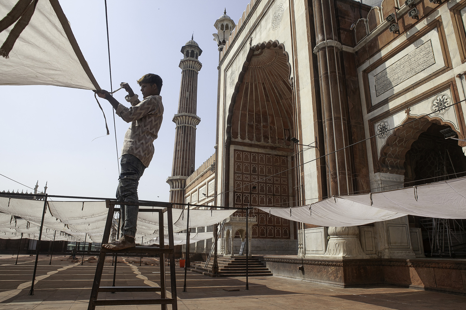 A person sets up canopies at a mosque in Delhi.