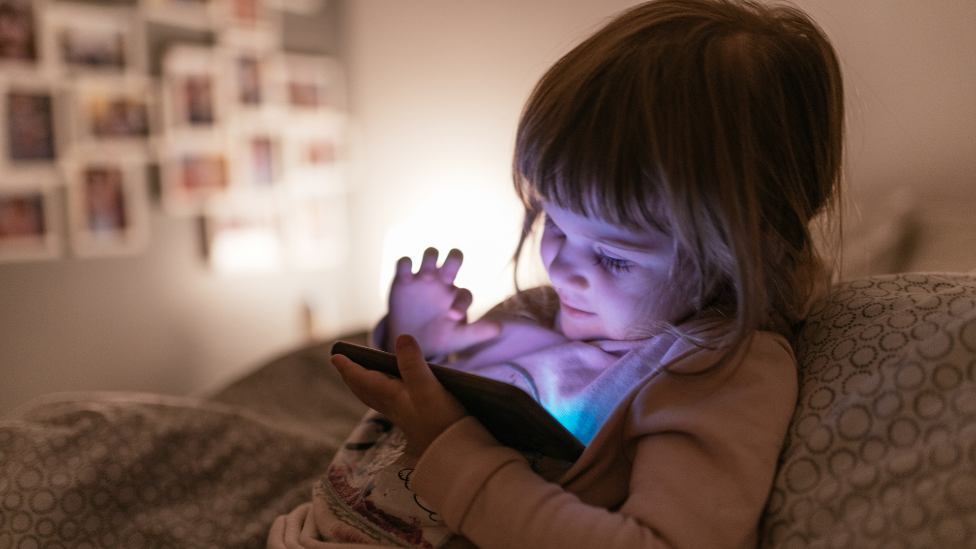 A youngster perches in bed while engaging with a mobile device.