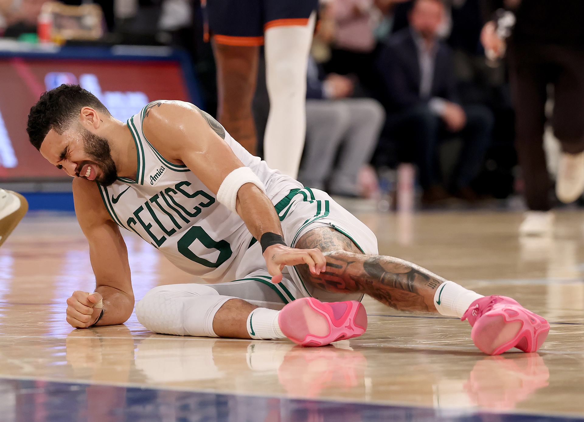 Jayson Tatum of the Boston Celtics grips his leg in distress on the court after sustaining an injury during the playoff match against the New York Knicks.