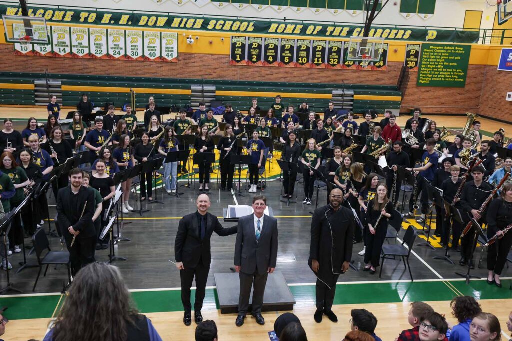 Jason Fettig, Stephen DeRees, music education instructor at H. H. Dow High School, and DaJuan Brooks, a doctoral student at U-M, with the combined band of college and high school students.