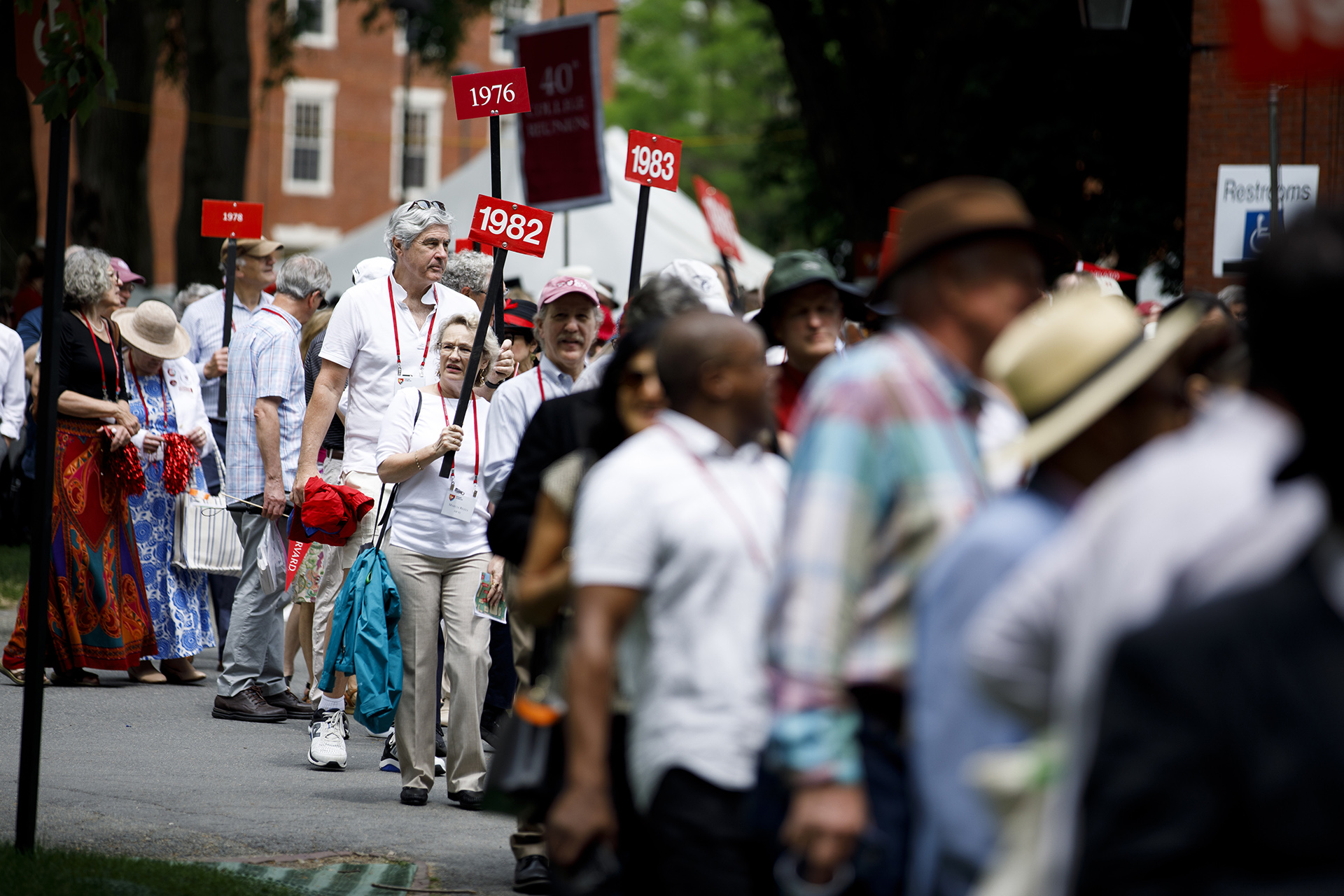 Alumni carrying signs with their year enter Harvard Yard.