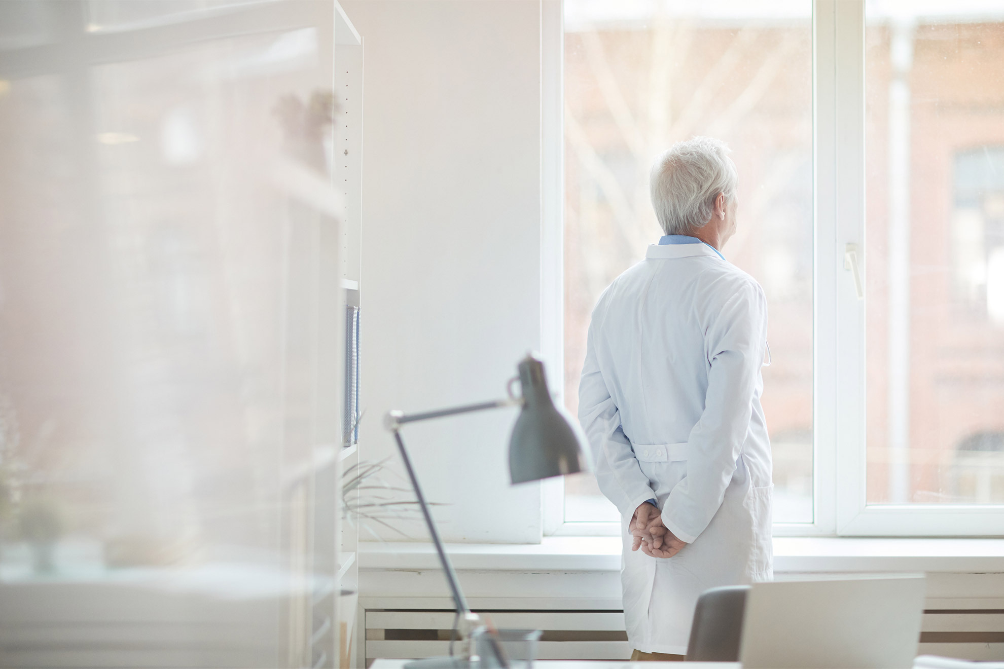 Senior doctor gazing out of a window.