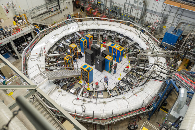 a large magnetic ring in a research laboratory. Within the ring are structures and individuals are engaged in work on them.
