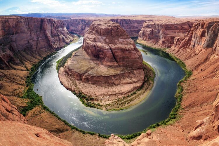 A river curves around reddish rocks.