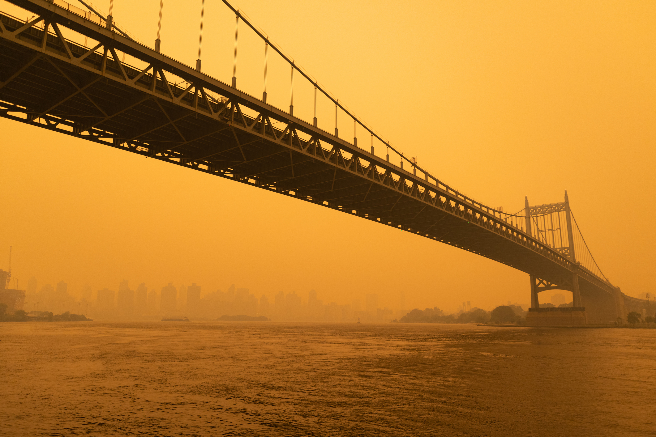 Orange smoke envelops a New York City bridge.