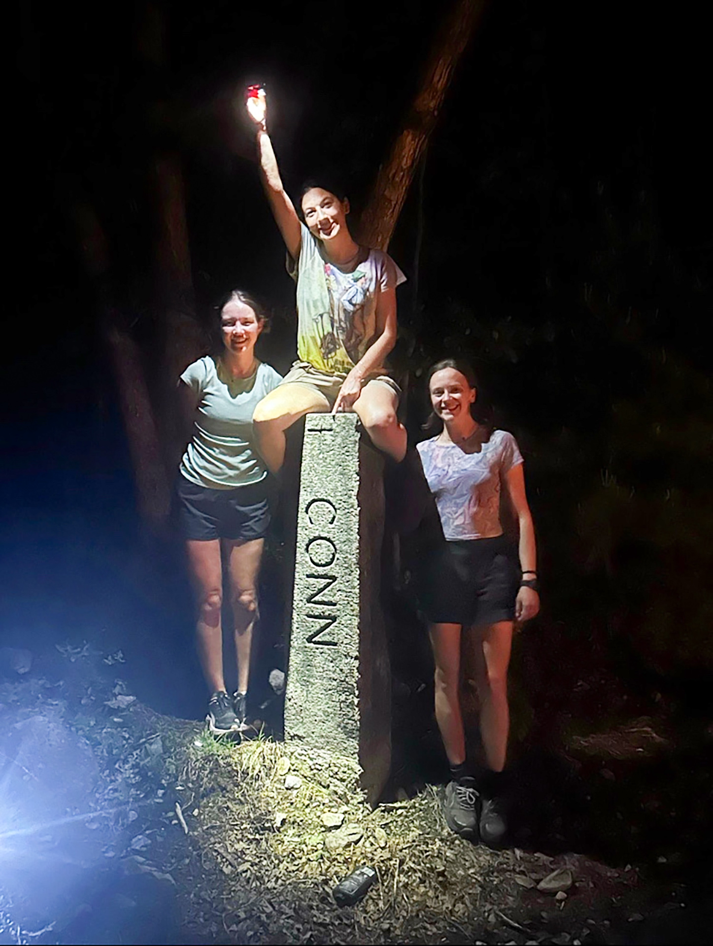 Eden Fisher, Amelia Heymach, and Addie Kelsey pose beside a Connecticut mile marker.