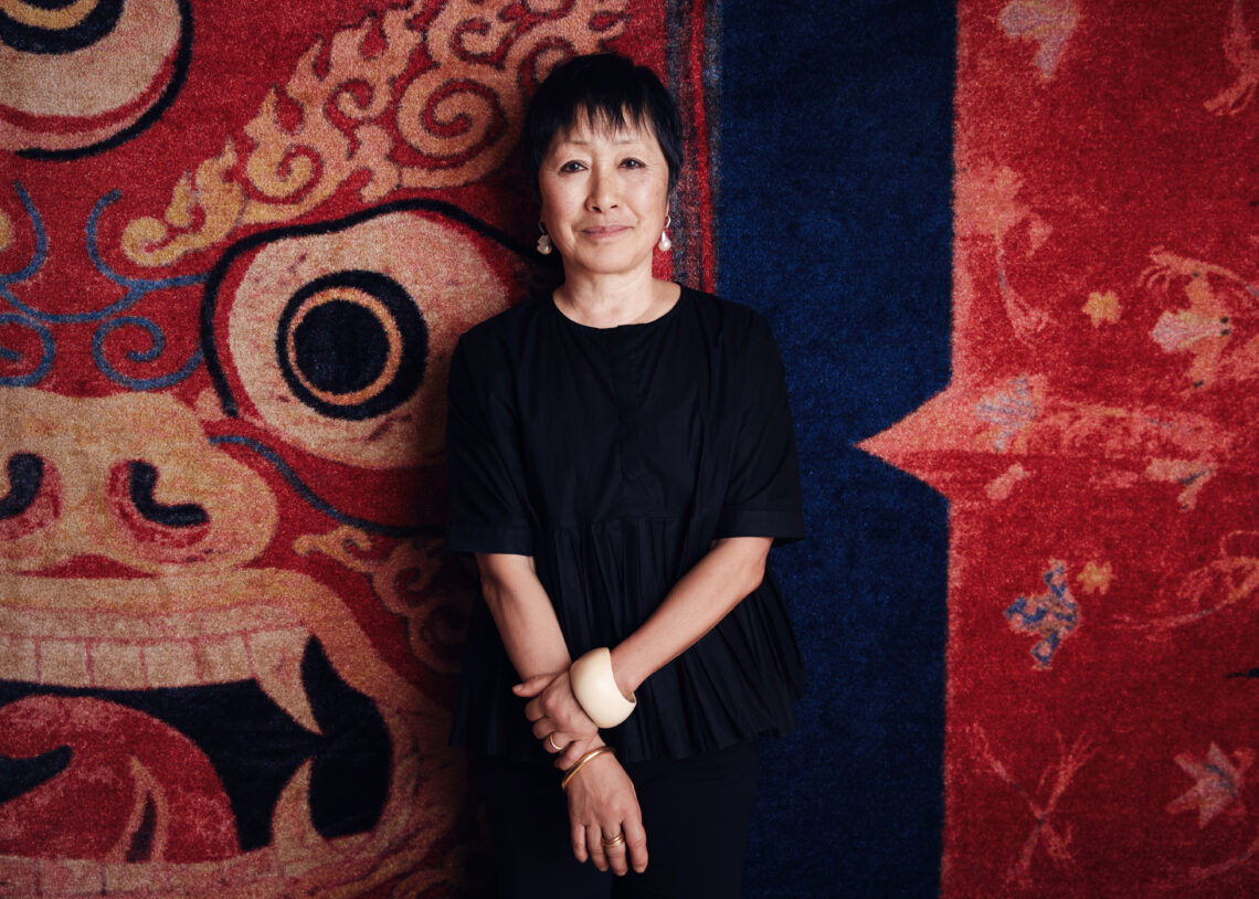 Asian woman standing before a rug