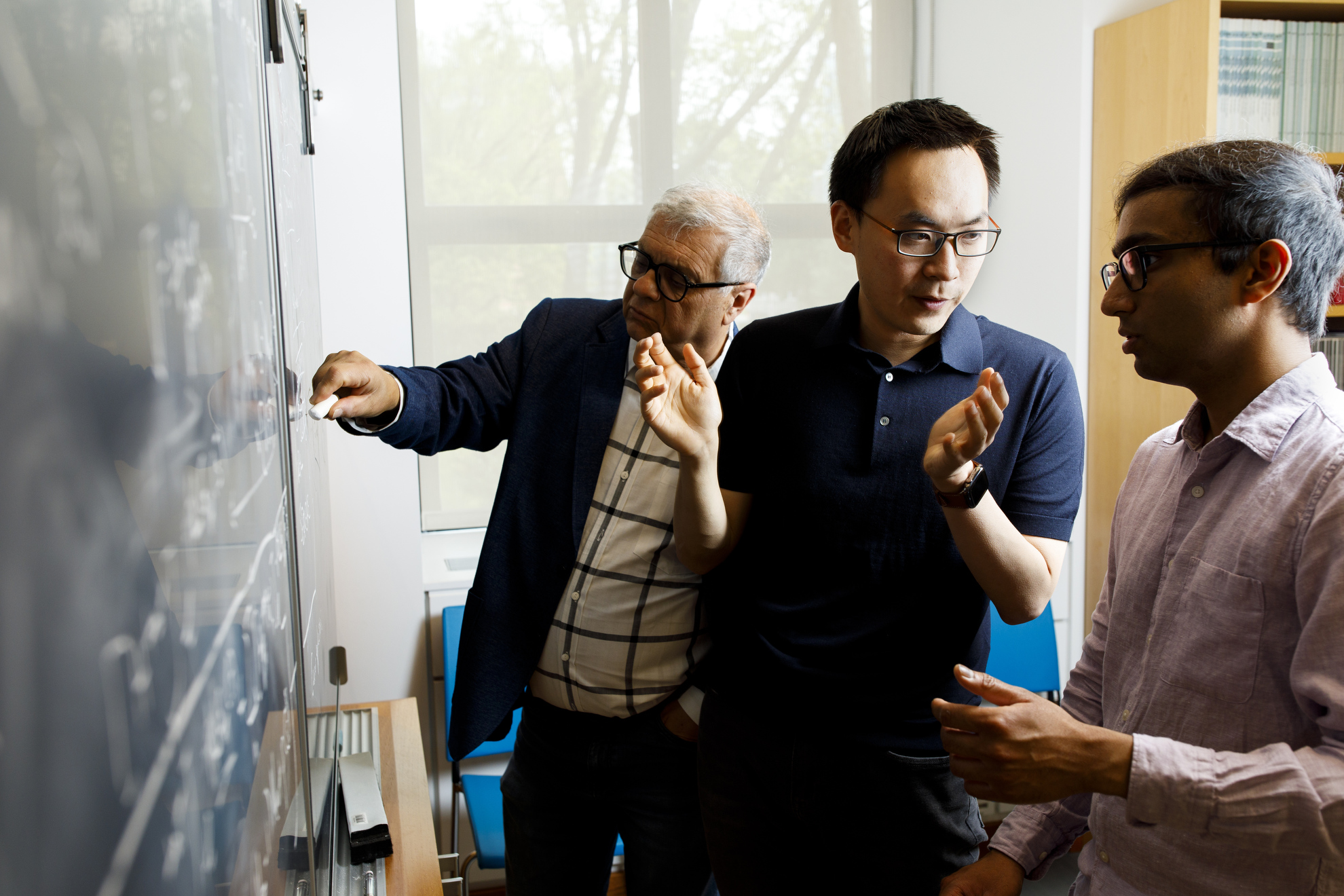 John Wang (center) shares insights from his coronavirus research with Eugene Shakhnovich (left), and doctoral student Vaibhav Mohanty (right)