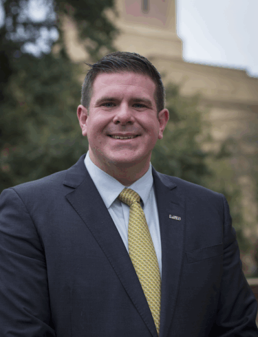 portrait of a man in a blue suit with a gold tie