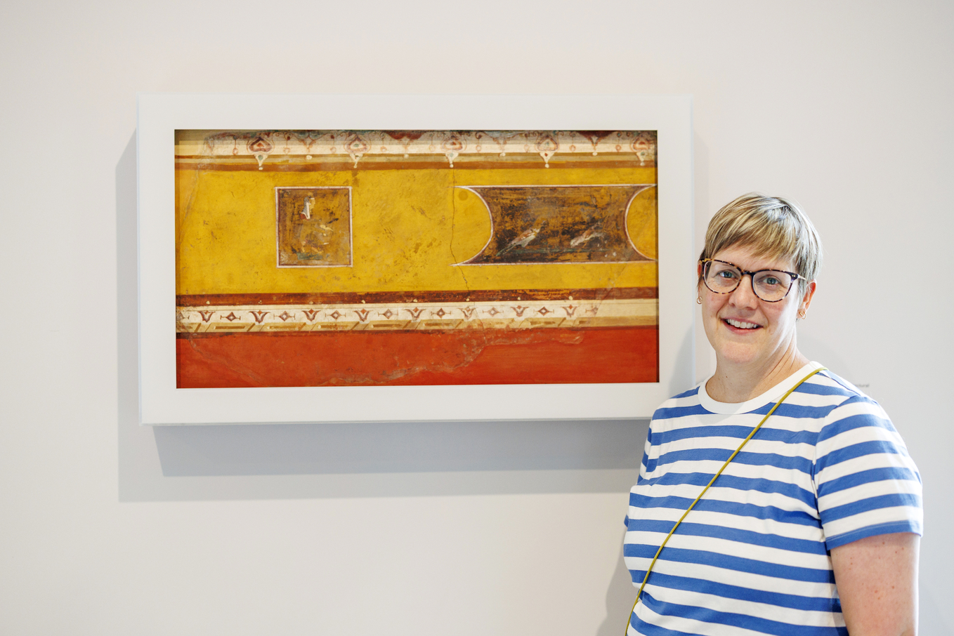 Kate Smith stands near Wall Painting Fragment from the Villa at Boscotrecase, 10 BCE-1 BCE, from the early Roman Imperial era.