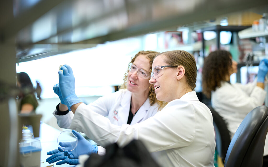 Christina Stallings, PhD (left) collaborates with postdoctoral research associate Abigail Garrett, PhD. In the Stallings lab, researchers investigate how <i>M. tuberculosis</i> defends itself against the immune system and withstands antibiotic treatment. (Photo: Matt Miller/WashU Medicine)” class=”wp-image-710042″  sizes=”auto, (max-width: 1024px) 100vw, 1024px”><figcaption class=