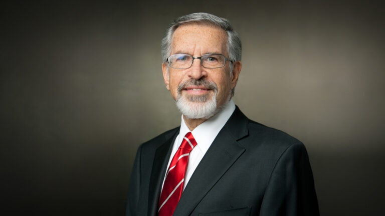 Leonard D. Schaeffer, wearing a dark suit and crimson tie, set against a simple backdrop.