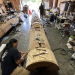 A narrative pole being sculpted in a workshop
