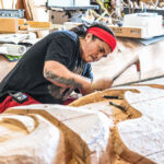 A narrative pole being sculpted in a workshop