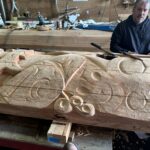 A narrative pole being sculpted in a workshop
