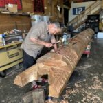 A narrative pole being sculpted in a workshop