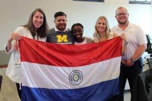 Javier Franco Duarte holds the Paraguayan flag alongside U-M students and faculty members. Image credit: Juan Ochoa