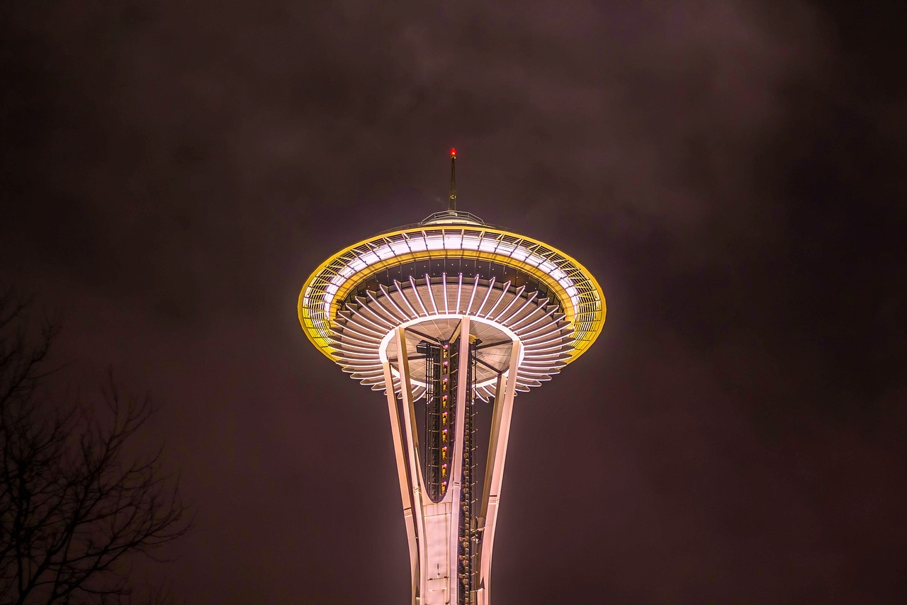 The Space Needle illuminated against a cloudy evening sky